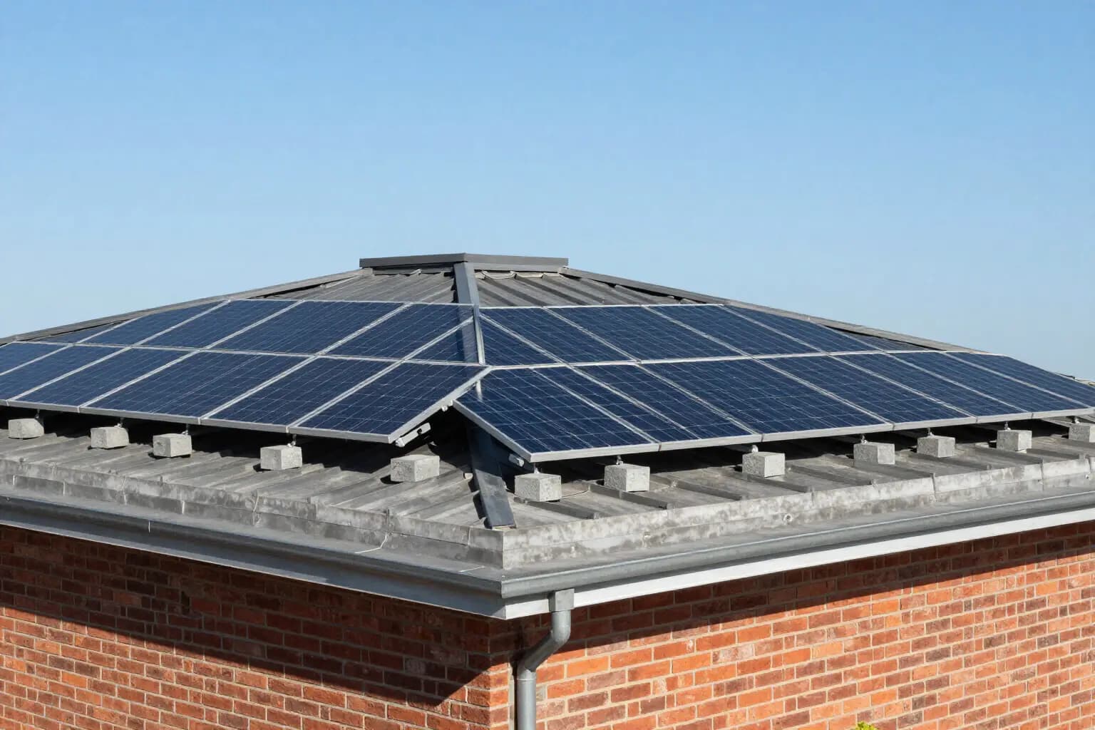 Rows of tilted solar panels on a flat roof, held down by concrete blocks