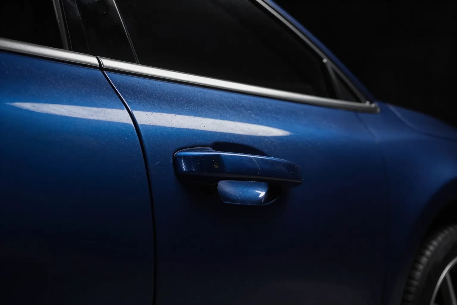 Dark blue door panel with swirl marks, water spots and a dull haze