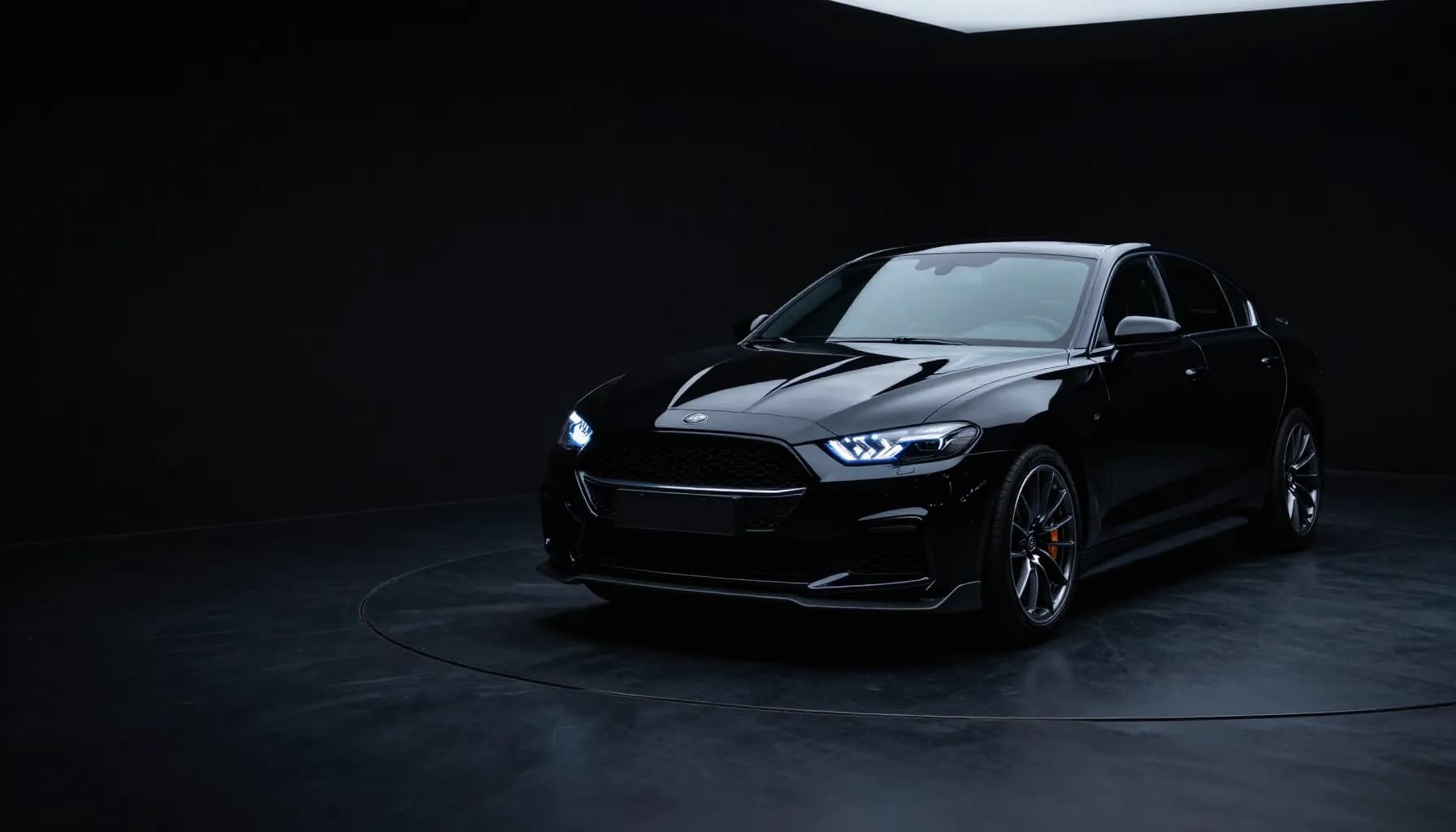 Black sports sedan in a dark studio, with a cool blue light along the headlights and long reflections on the paint